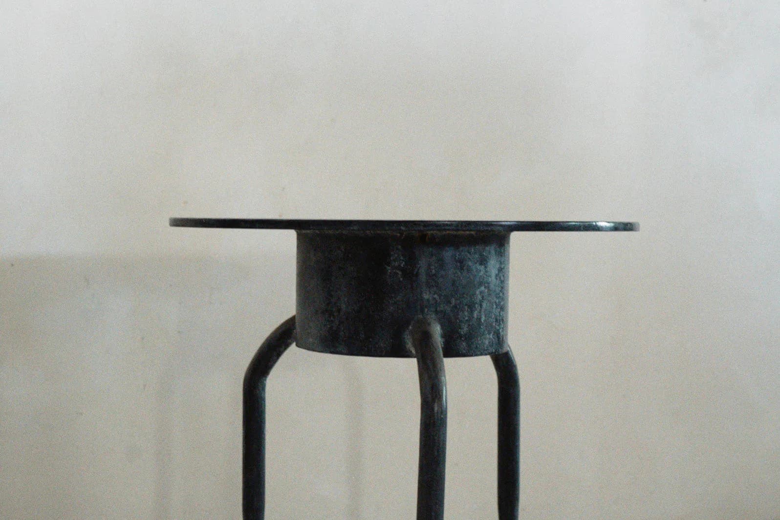 Dark metal sculptural object with cylindrical form and extended horizontal elements on thin legs, minimalist industrial design by Cal Summers.