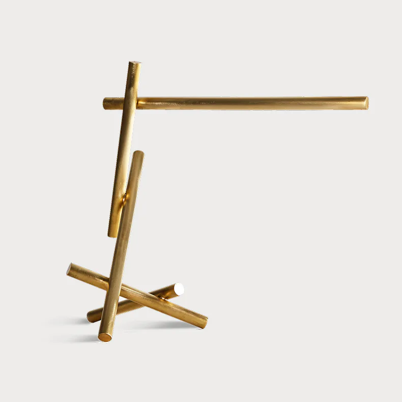 Brass sculptural installation with intersecting cylindrical forms and geometric cross elements, minimalist metalwork design by Cameron Crockford.
