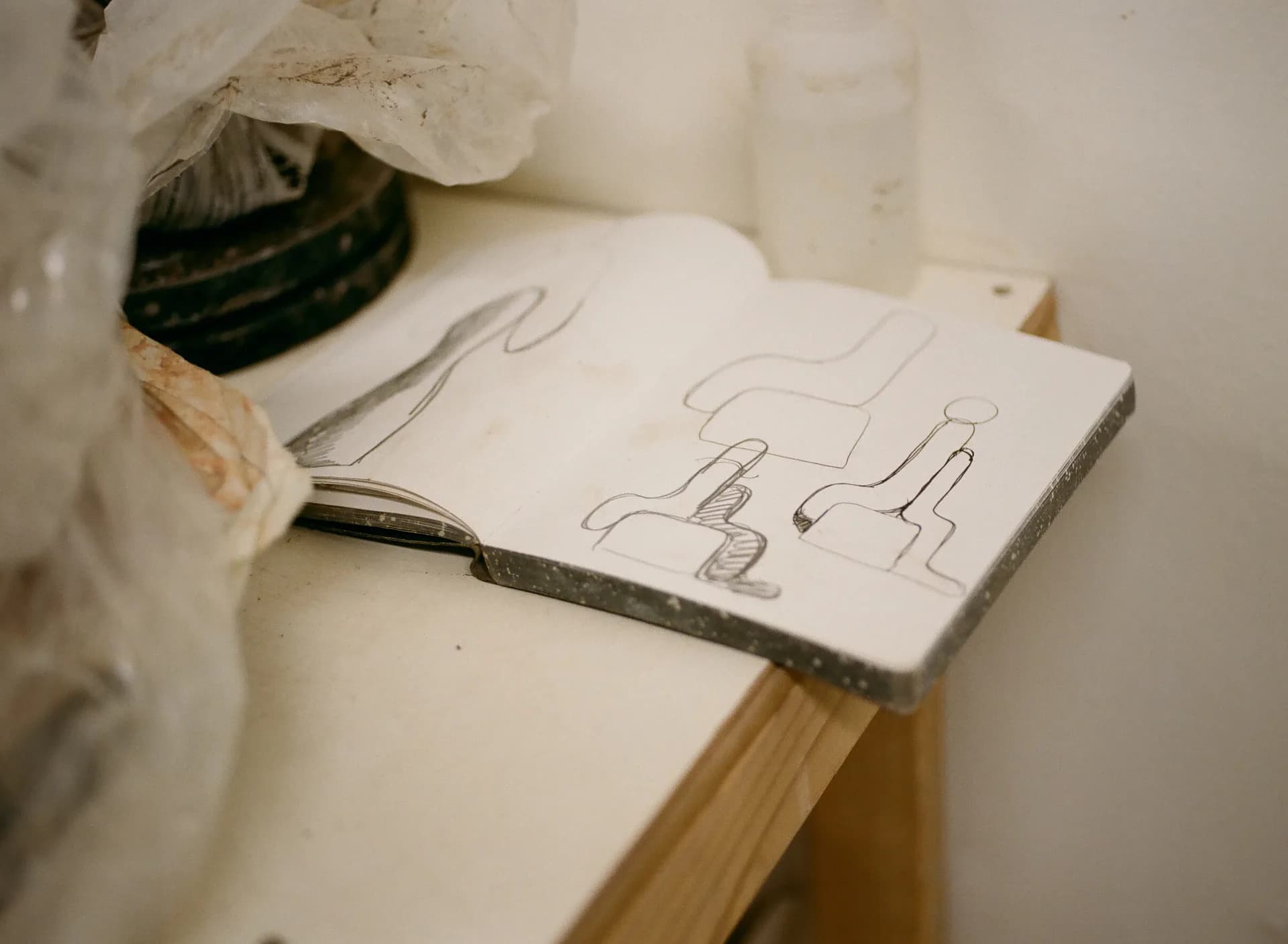 Architectural sketch on white paper showing hand-drawn furniture elevations and details, displayed on a wooden surface by Carmen D'Apollonio.
