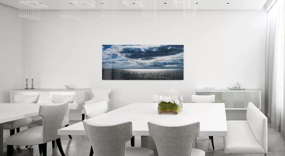 Modern minimalist dining room with white curved table, gray upholstered chairs, and landscape artwork by Carol Brewer.