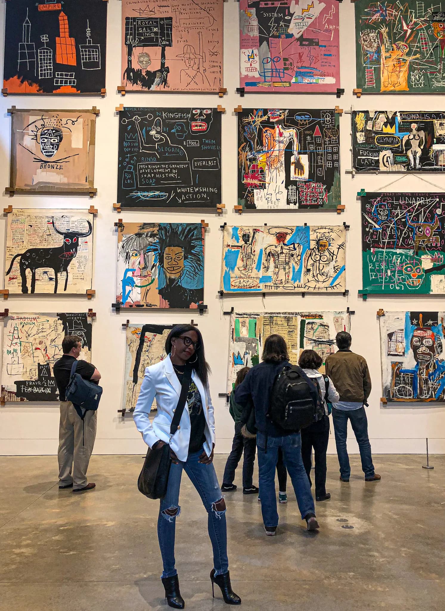Gallery exhibition of colorful abstract and figurative artworks displayed on white walls, with visitors viewing the installation by Cassandre Bonhomme.