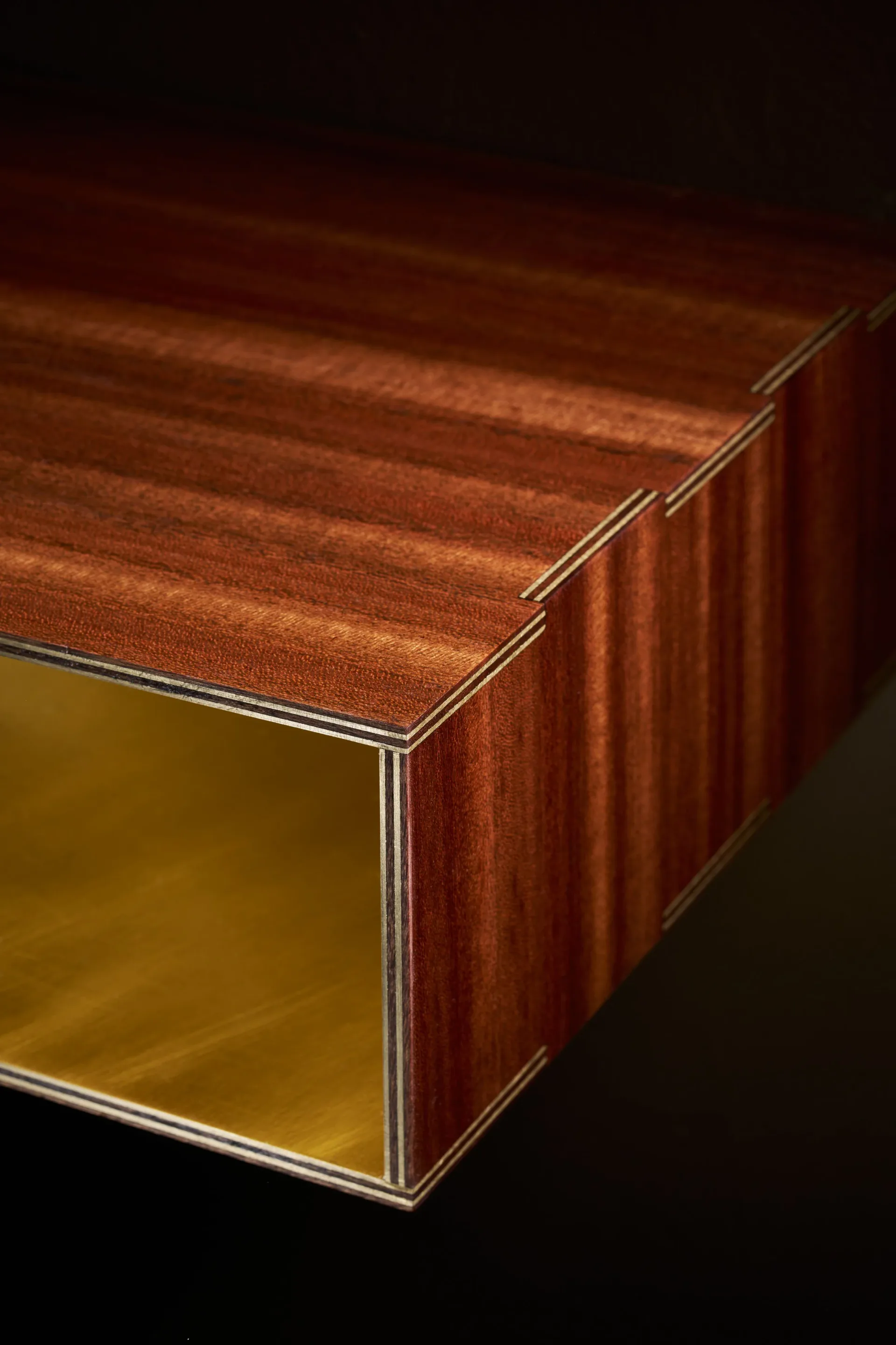 A wooden box or cabinet with warm mahogany veneer, brass inlay details, and a golden interior visible through an open front panel, rendered with polished surfaces and dramatic lighting by Charles Grantham.