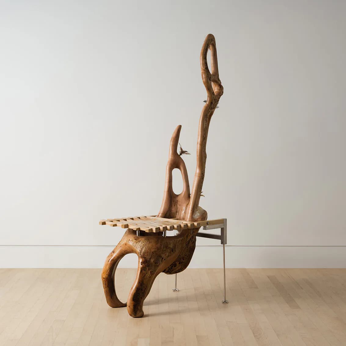 Sculptural wooden chair with organic, curved forms and an integrated side table, crafted from natural wood in warm tones by Chen Chen.