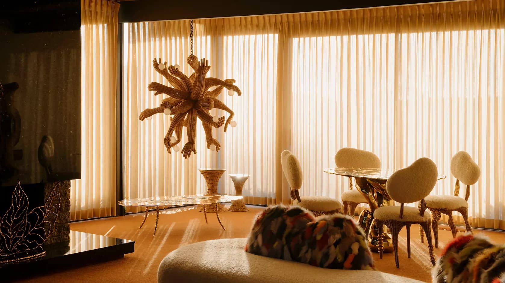Warm-toned modern interior with wood flooring, sculptural dried-flower arrangement, mid-century chairs, and floor-to-ceiling vertical blinds by Chris Wolston.