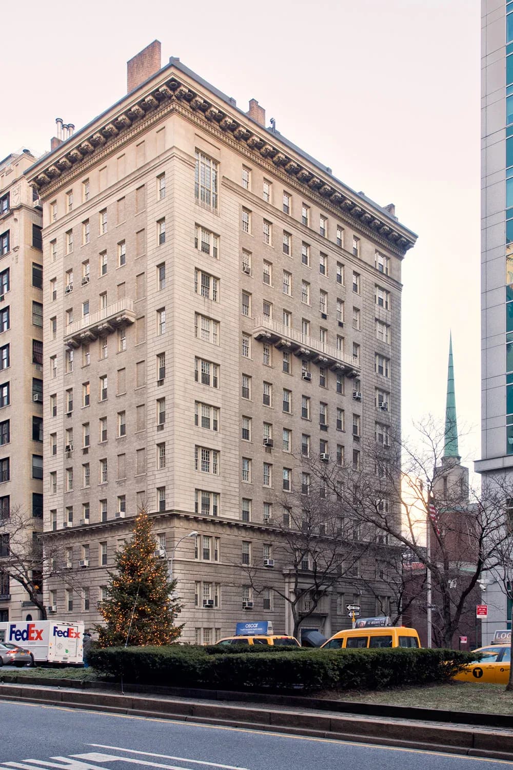 Beaux-Arts facade of a twelve-story Manhattan residential building with rusticated limestone exterior, ornamental cornice, and street-level retail, by Christopher Scholz.