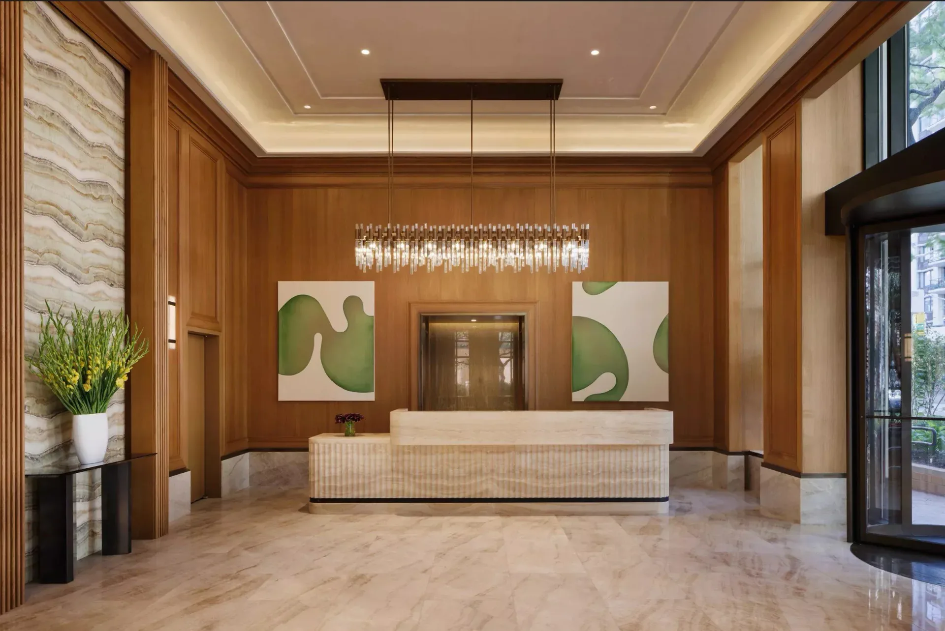 Luxury lobby interior with warm wood paneling, marble flooring, modern reception desk, and abstract artwork by Christopher Sondi.
