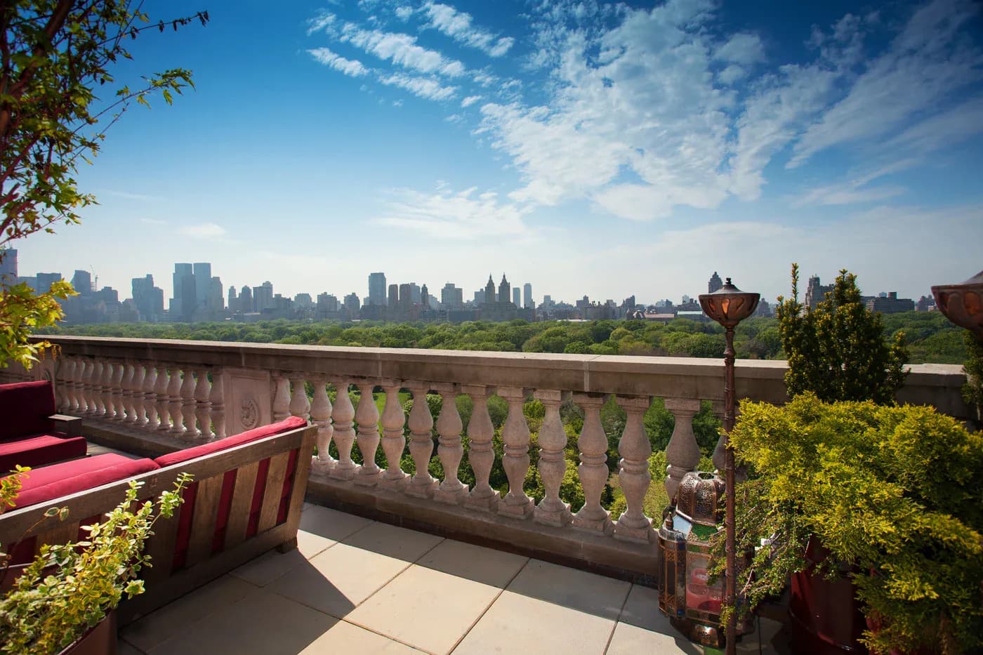 A rooftop terrace with ornamental balustrade overlooking the Manhattan skyline, featuring vibrant plantings and terracotta vessels by Clemence Bouchabake.