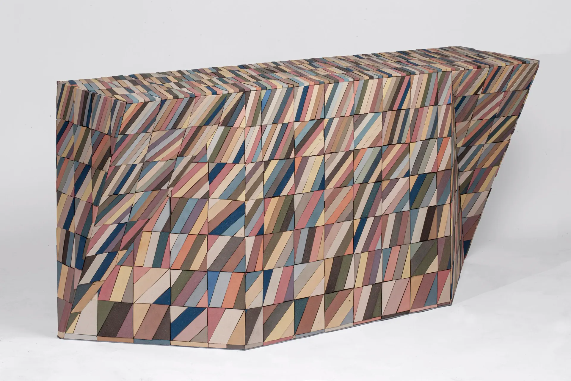 Abstract geometric patterned sculptural form with interlocking triangular segments in blue, tan, pink, and gray tones by Cody Hoyt.