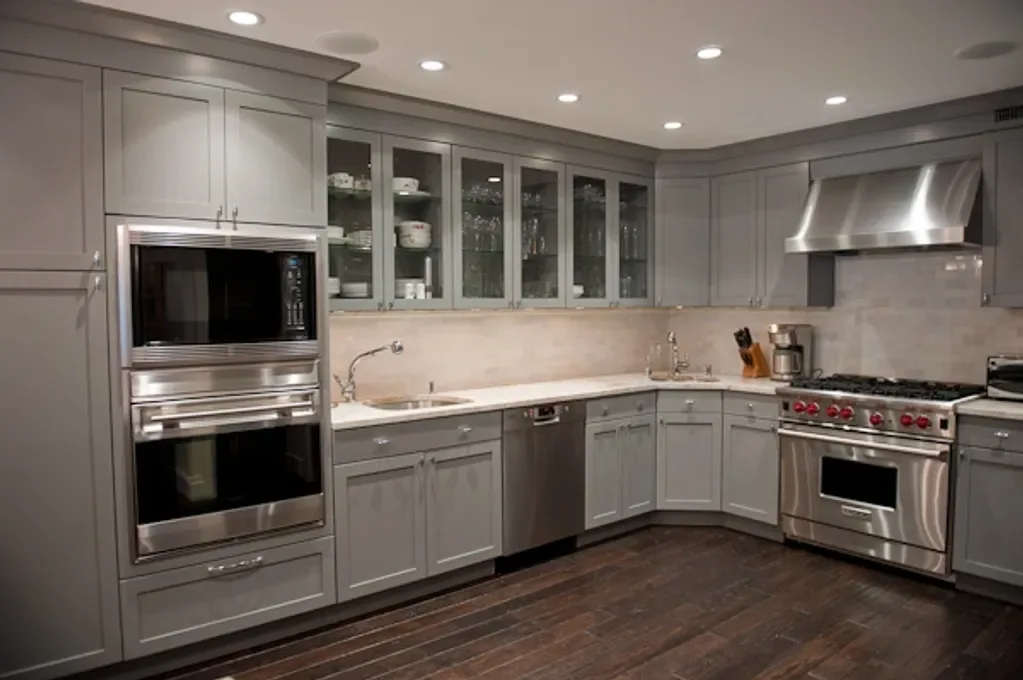 Modern kitchen with gray cabinetry, stainless steel appliances, white countertops, and recessed lighting by Cori Thune.