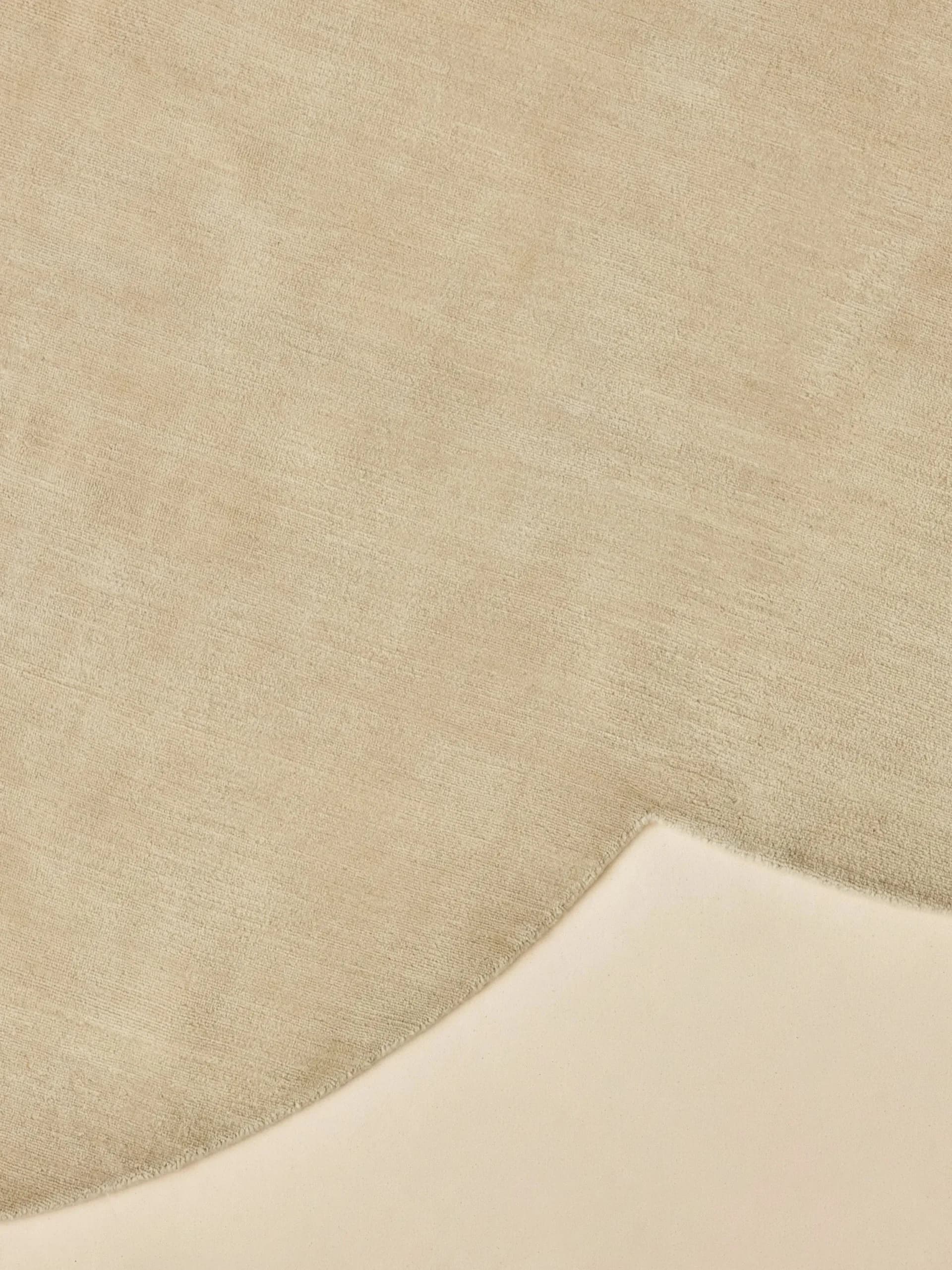 Minimalist interior detail showing layered neutral textiles and curved architectural form in soft beige tones by Crystal Ellis.