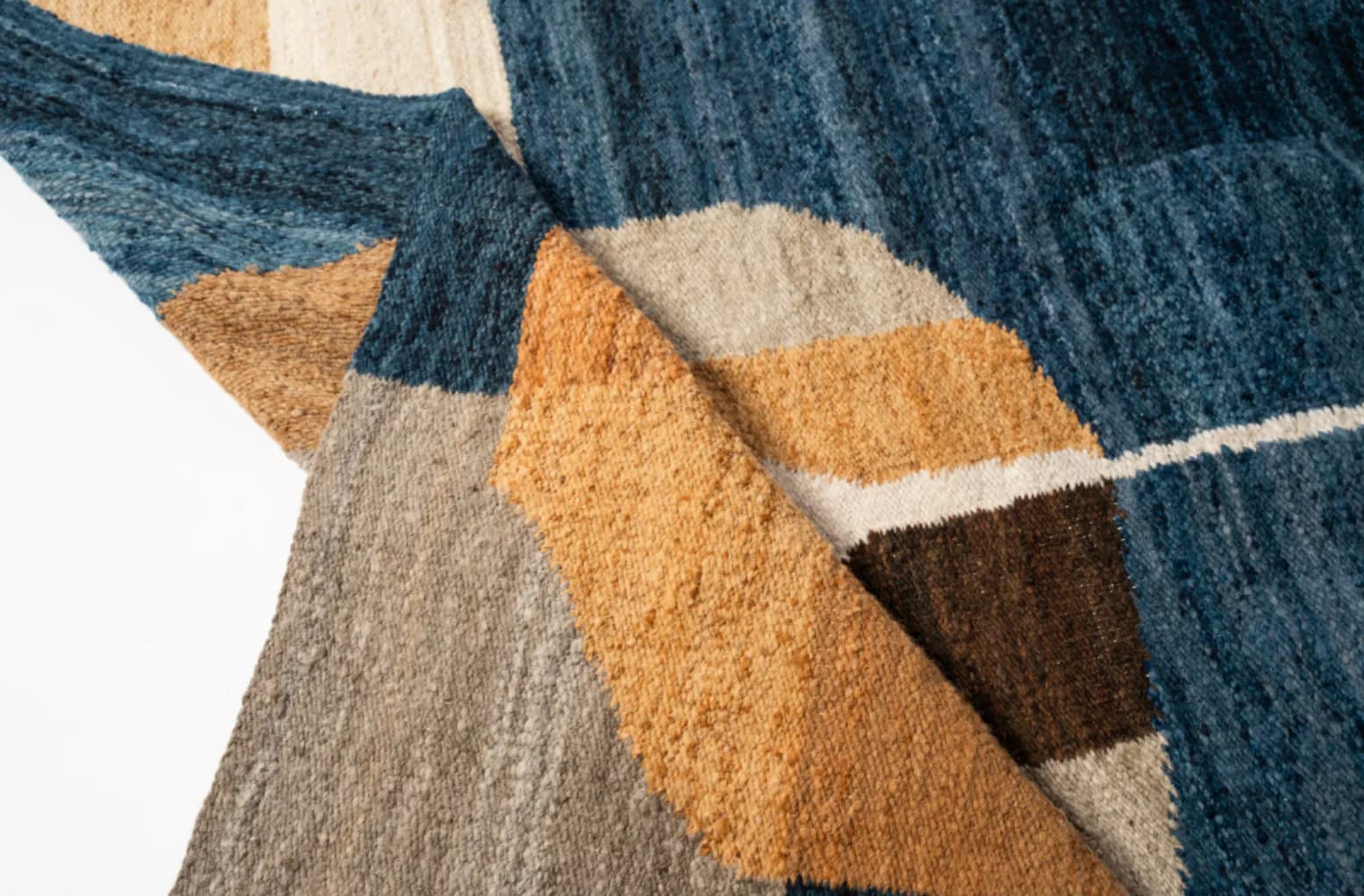 Close-up detail of a geometric patterned textile with navy, gold, beige, and brown blocks in an abstract composition by Dalia Forman.