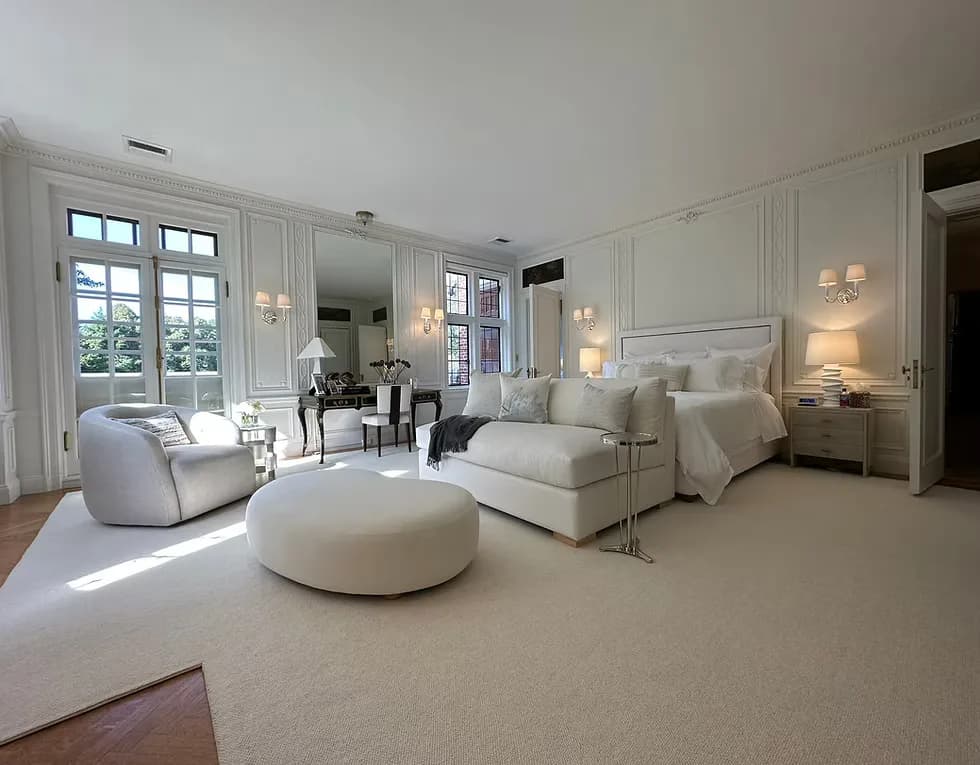 Luxurious master bedroom suite with cream and beige palette, featuring upholstered bed, modern furnishings, and French doors opening to terrace by Dalton Scott.