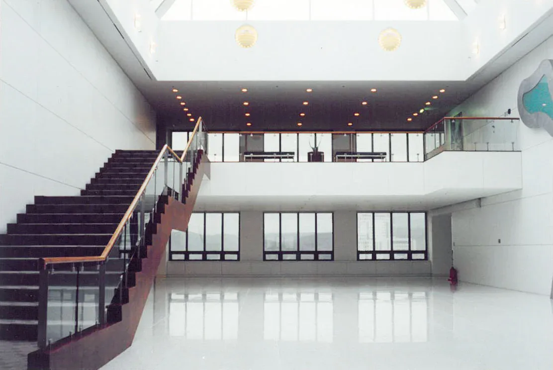Modern multi-level interior with burgundy staircase, white walls, and floor-to-ceiling windows under a coffered ceiling with recessed lighting by Damiano Geraci.