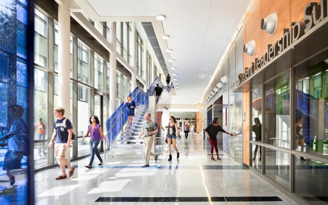 Bright modern retail corridor with blue accent wall, central staircase, and storefronts by Dana McCarty.