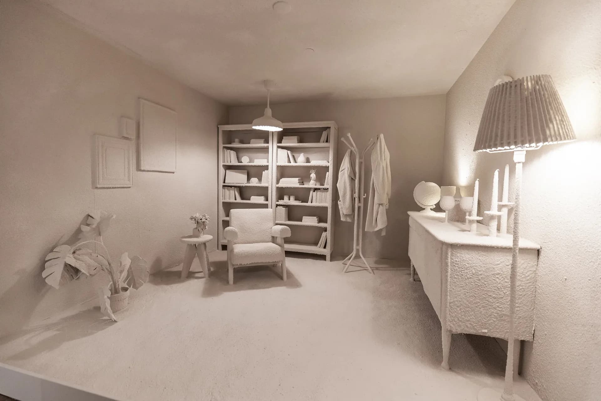 All-white minimalist bedroom interior with monochromatic furniture, shelving, and decor by Daniel Arsham.