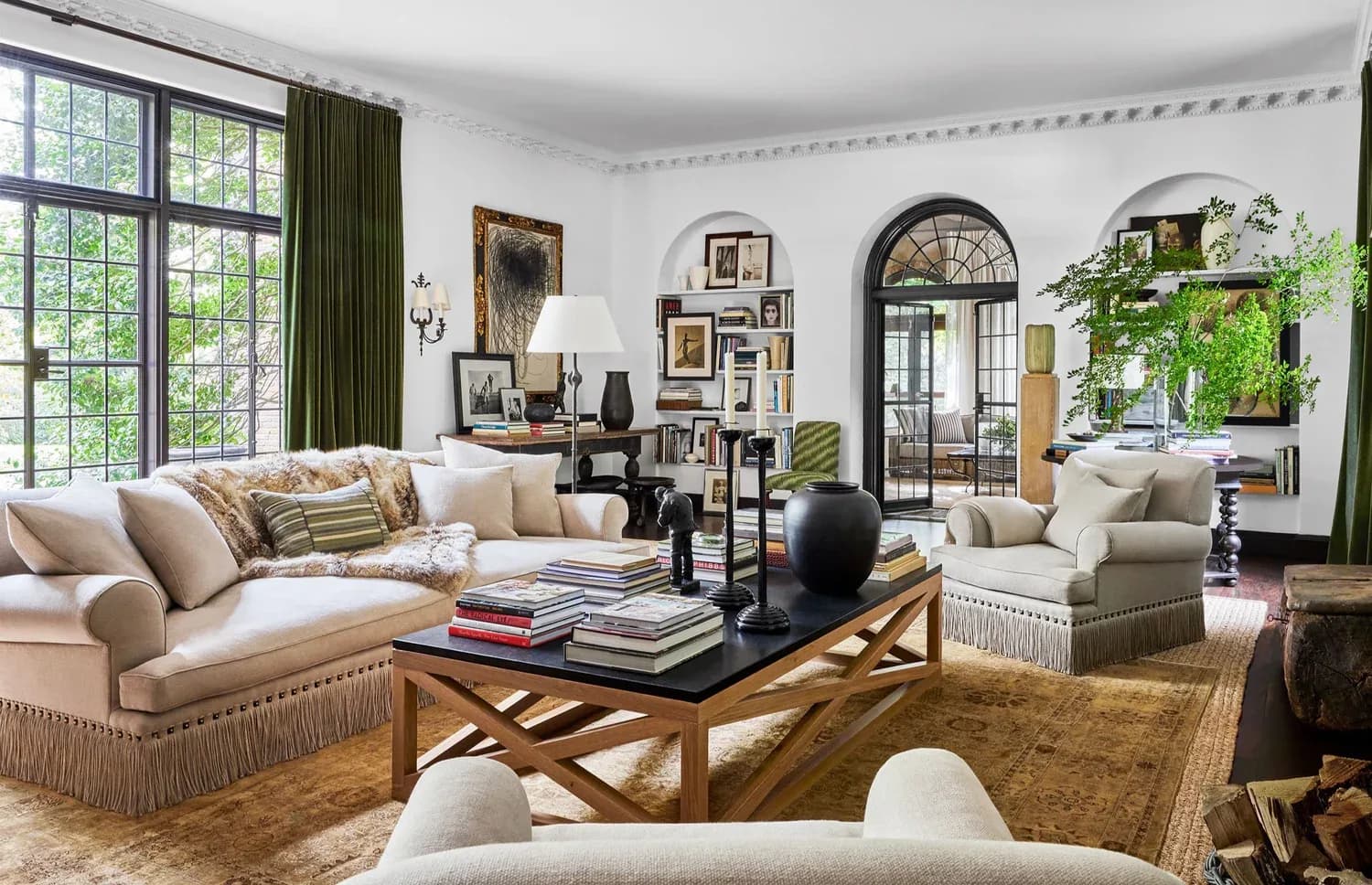 Elegant living room with cream upholstered seating, black coffee table, arched doorways, and curated gallery wall, designed by Danielle Peterfy.