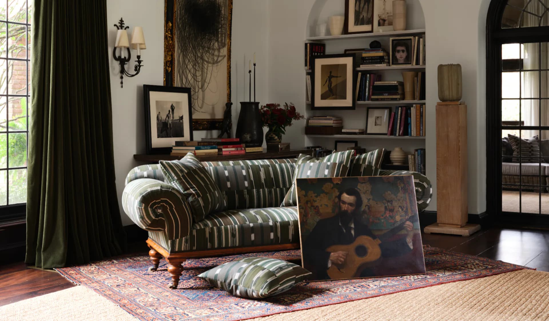 Eclectic living room featuring a striped Chesterfield sofa, patterned area rug, gallery wall, and vintage furnishings in warm earth tones by Danielle Peterfy.