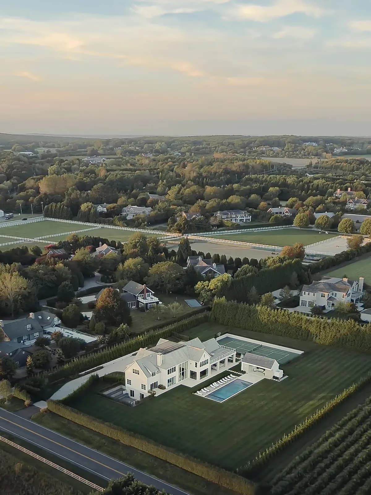 Aerial view of a contemporary white residential estate with pool set on manicured grounds overlooking pastoral countryside by Danny Little.