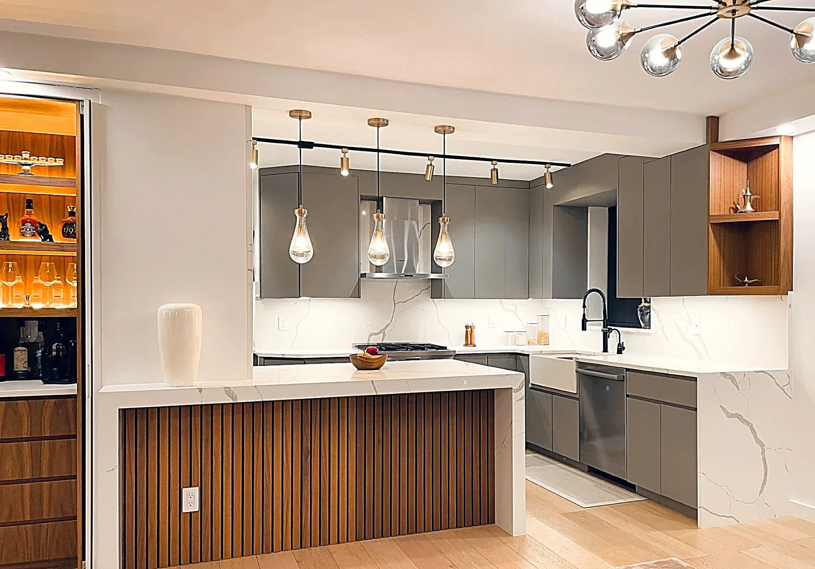 Modern kitchen with gray cabinetry, white marble countertops, wood-paneled island, and pendant lighting by Daria Demin.