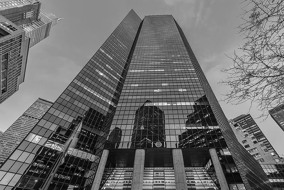 Modernist skyscraper facade shot from ground level, featuring geometric gridded glass and metal panels with dramatic upward perspective by David Jhee.