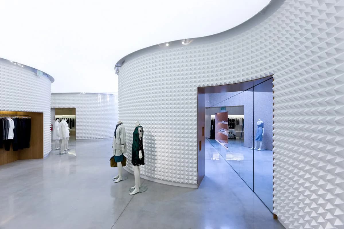 Modern retail interior with curved white textured walls, polished concrete flooring, and blue-lit storefront display by Dina Reziapova.
