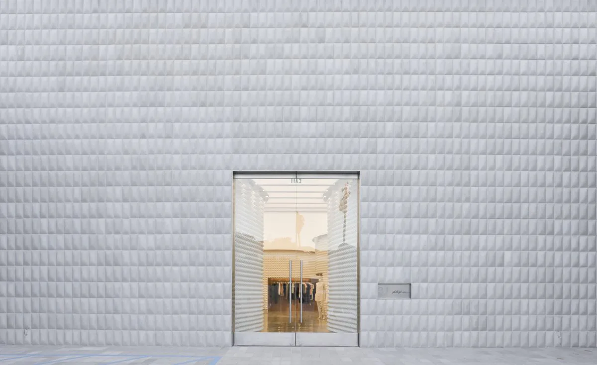 Minimalist white brick facade with centered glass door and warm interior lighting, architectural rendering by Dominic Leong.