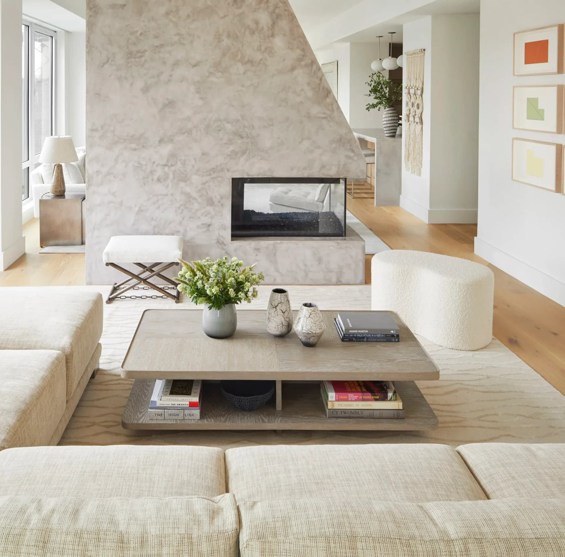 Modern living room with marble fireplace, cream upholstered seating, wooden floors, and minimalist décor by Dyana Kazan.