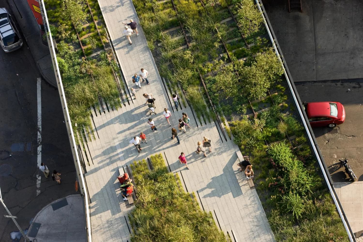 Aerial view of the High Line elevated park featuring planted gardens, concrete walkways, and visitors strolling through green spaces designed by Elizabeth Diller.