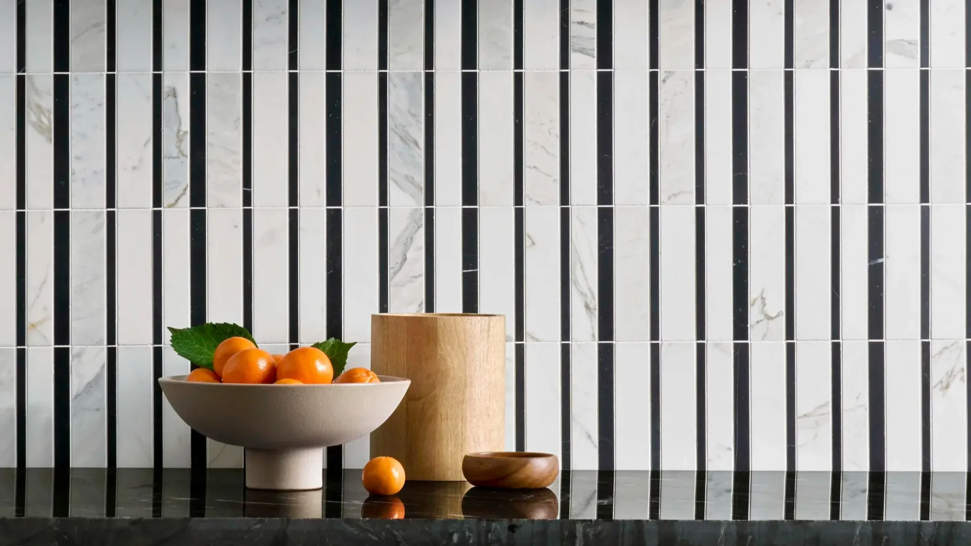Minimalist still life with ceramic bowl, wooden cylinder, and apricots against striped marble backdrop by Emeryann Hare.