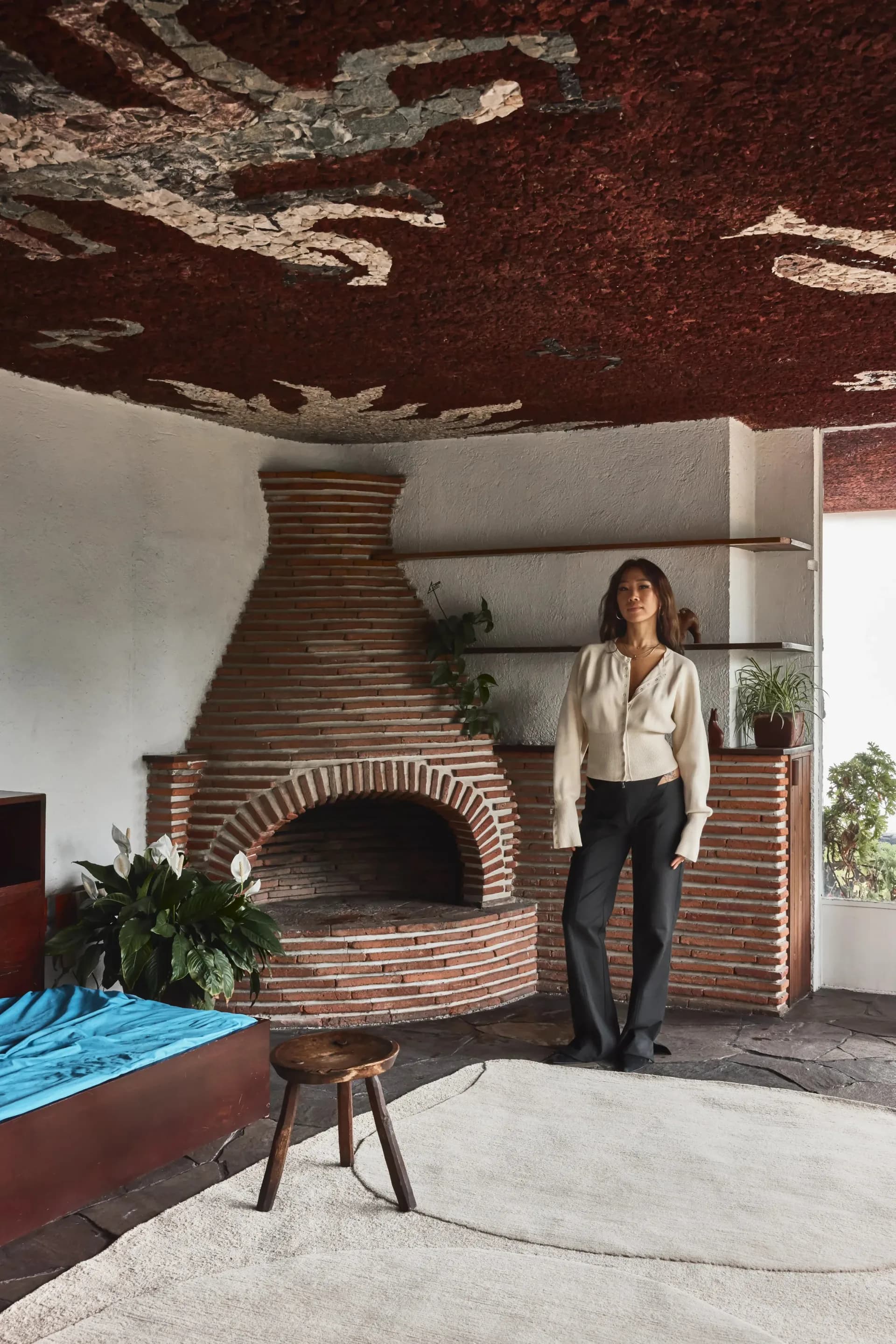 Brick fireplace with curved archway and wooden shelving in minimalist interior with exposed ceiling by Eny Lee Parker.