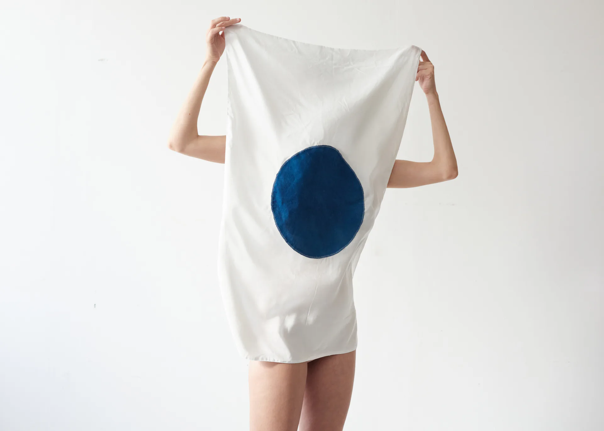 White t-shirt dress with a bold navy blue circular motif displayed as a graphic design product by Erez Nevi Pana.