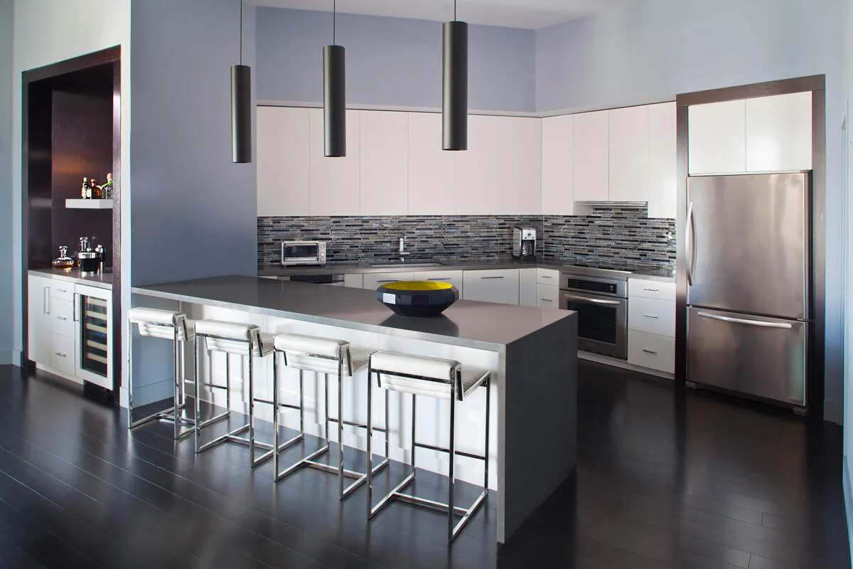 Modern kitchen with white cabinetry, dark striped backsplash, stainless steel appliances, and black island with seating by Eric Winnick.