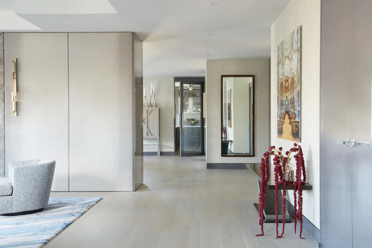 Modern minimalist hallway with light oak cabinetry, polished concrete flooring, and sculptural red furniture accent by Eric Winnick.