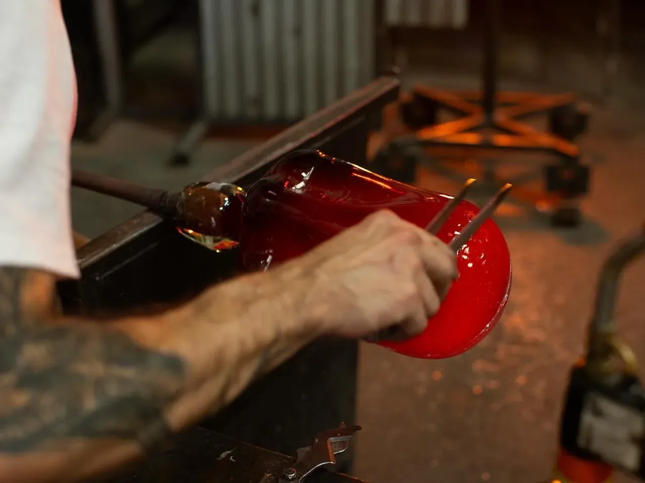 Artisan crafting a hand-blown red glass vessel with molten material, showcasing detailed glasswork technique by Esteban Salazar-Cucalon.
