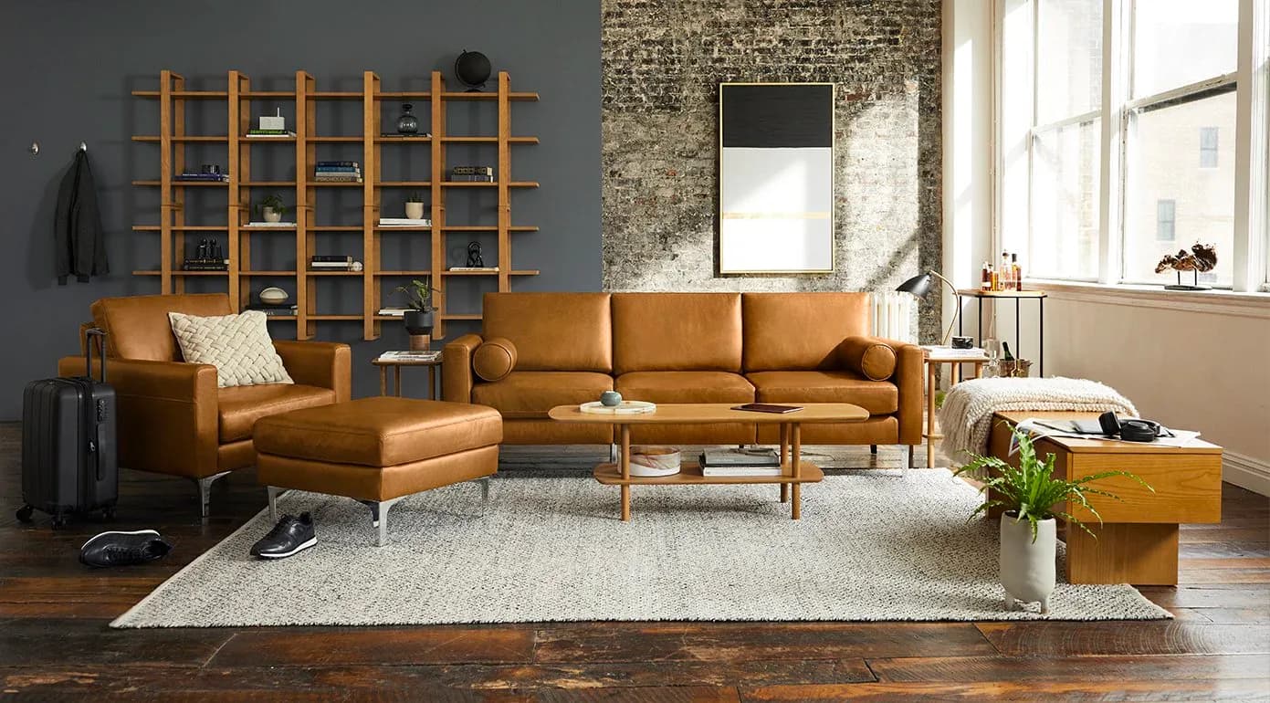 Modern living room with cognac leather sectional sofa, wooden grid shelving, and dark hardwood floors, designed by Evan Clabots.