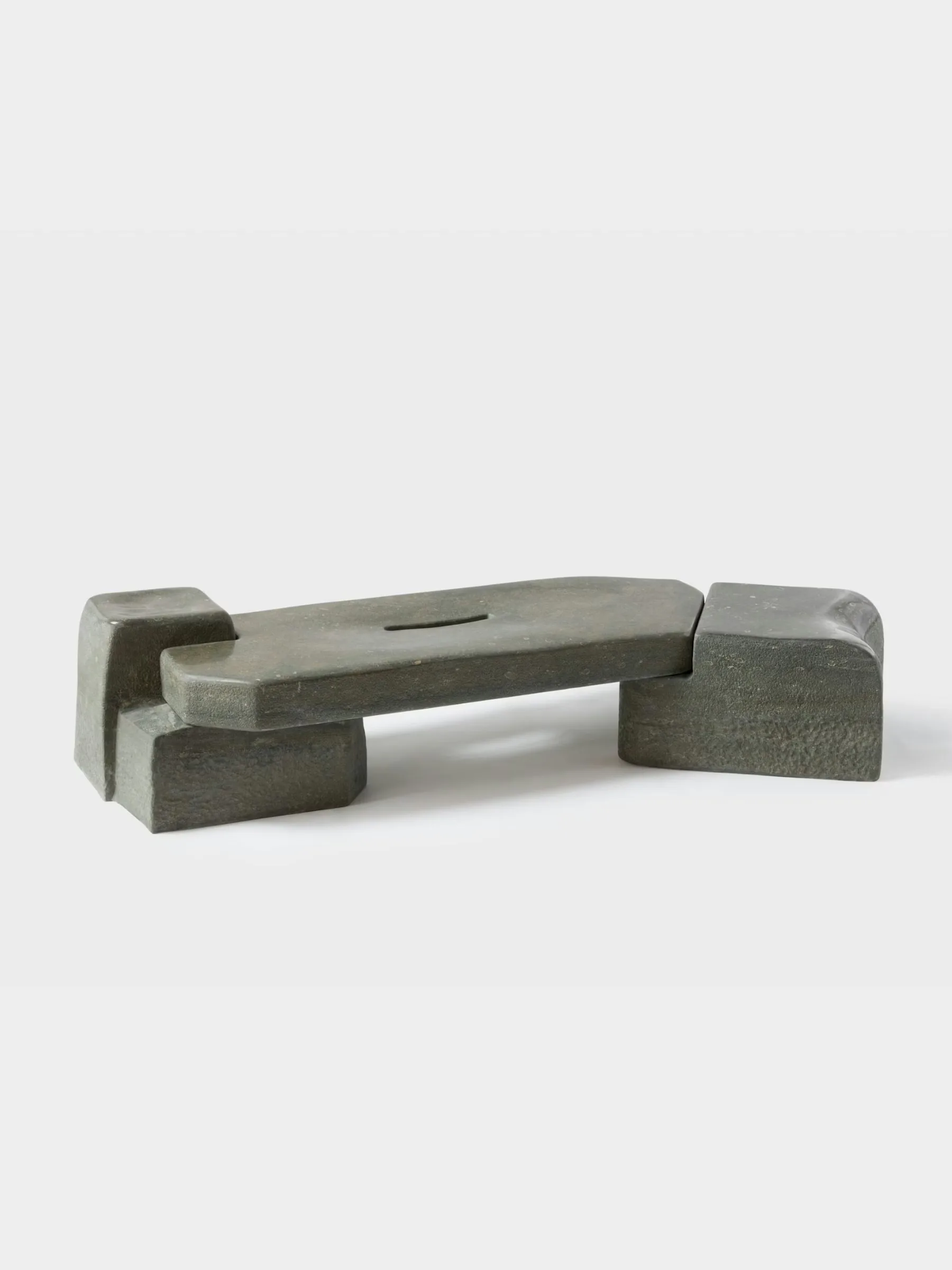 Concrete sculptural bench with integrated armrests and seat, featuring minimalist geometric forms and a muted grey palette, by Faye Toogood.