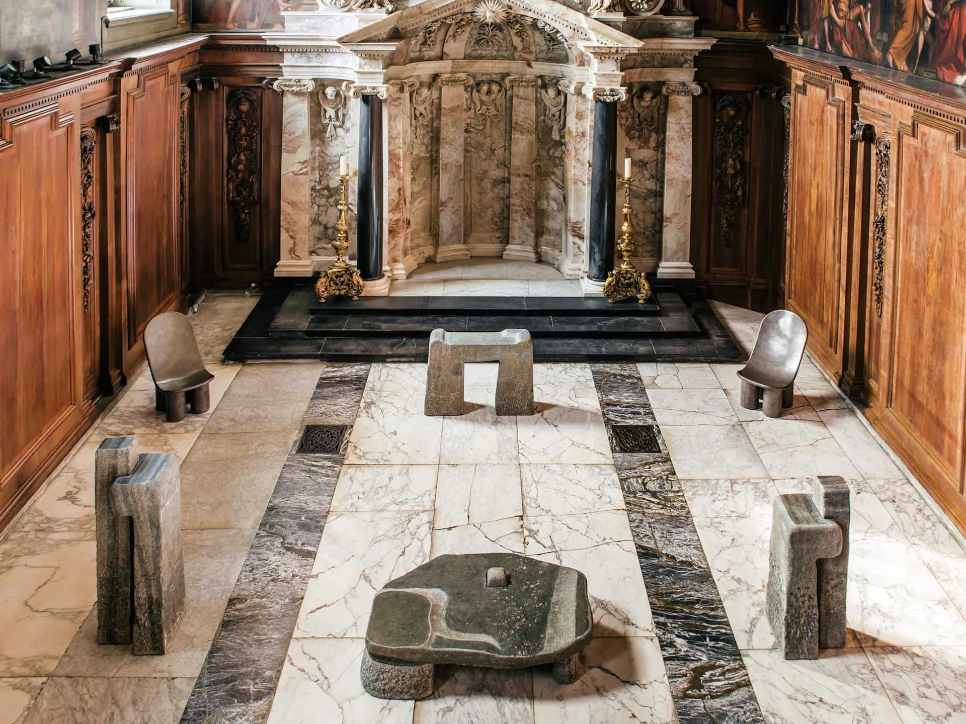 Classical chapel interior with marble flooring, stone altars, ornamental columns, and gilded religious artwork by Faye Toogood.