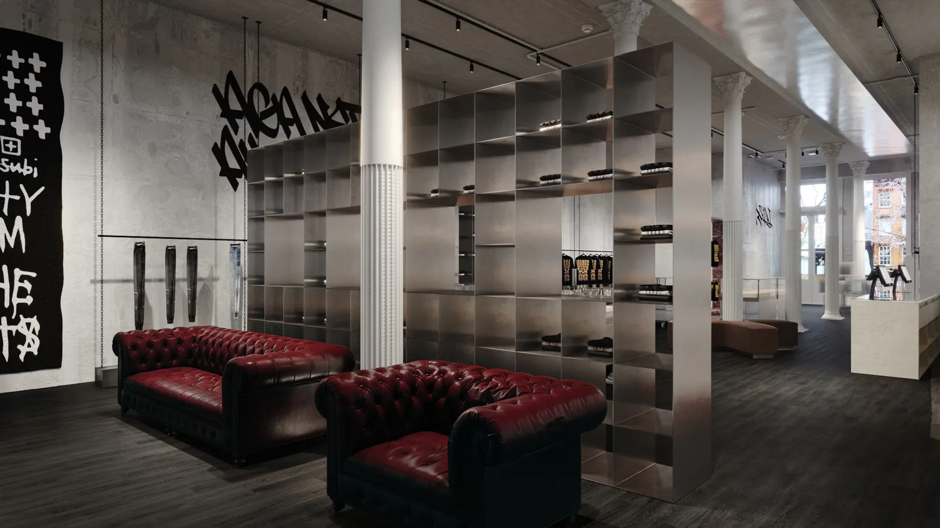Industrial loft interior with concrete walls, steel columns, burgundy leather Chesterfield sofas, metal shelving units, and graffiti-style wall art by Fernanda Ruelas.