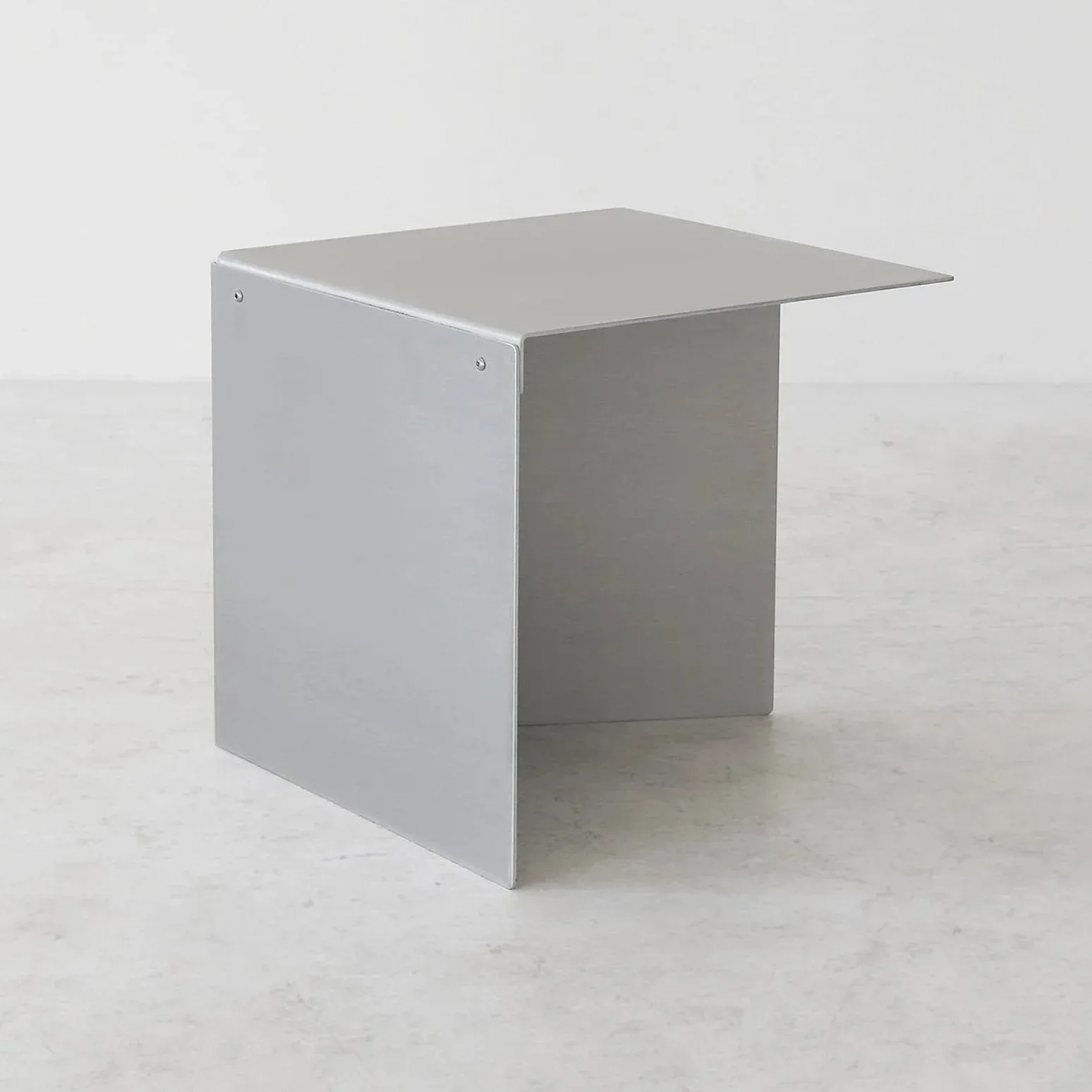 Minimalist gray metal desk or table with an angular top and open frame structure, photographed against a light background by Ford Bostwick.