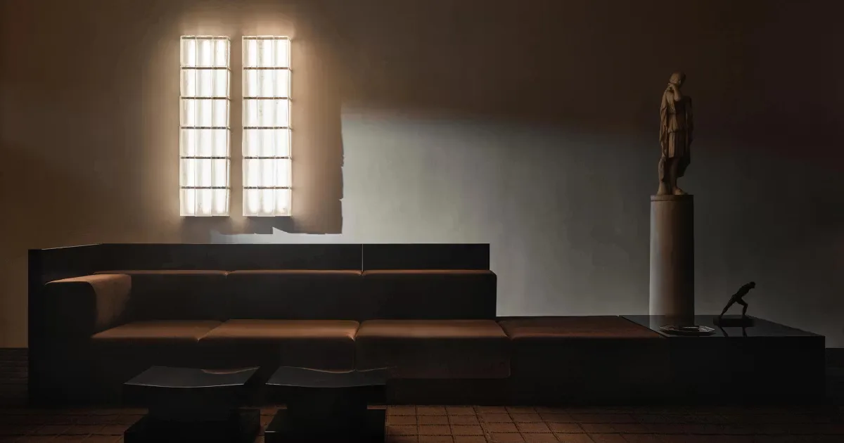 Minimalist interior with low-profile dark furniture, geometric window opening with grid pattern, and sculptural bronze figure on pedestal, designed by Gabriel Abraham.