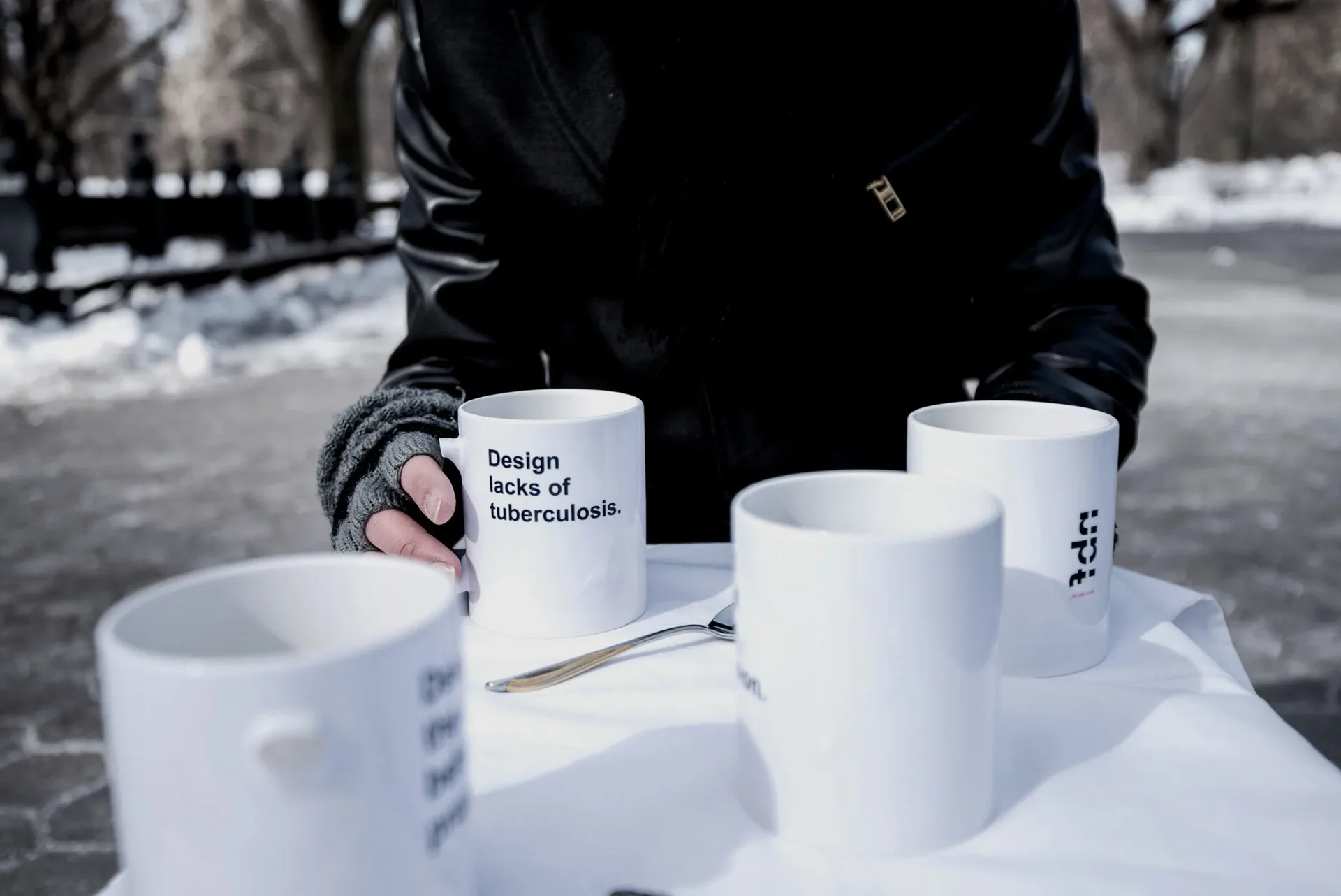 White ceramic mugs with minimalist typography displayed outdoors in winter, showcasing branding design work by Gabriel Colon-Amador.