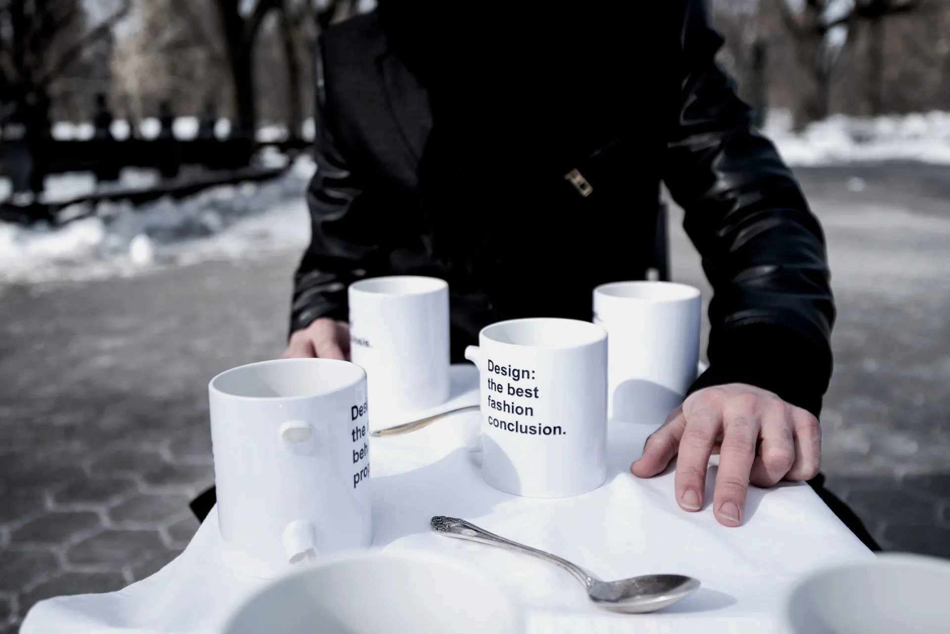White ceramic mugs with text arranged in a circular formation on snow, showcasing product design and typography work by Gabriel Colon-Amador.