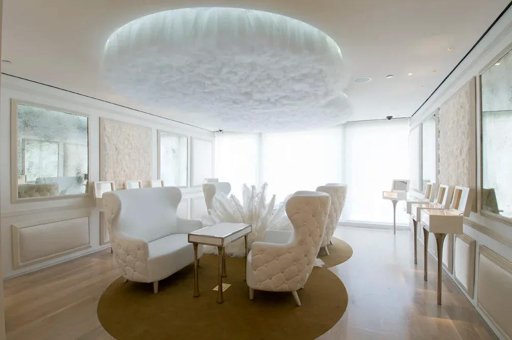 A luminous modern interior with cream-upholstered seating, circular olive-green floor element, and dramatic circular ceiling feature; design by Glen Lee.