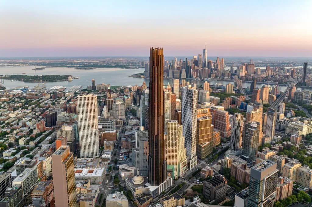 Aerial view of Manhattan's skyline at golden hour, featuring tall Art Deco and modern skyscrapers with the Hudson River and surrounding boroughs visible in the distance, by Gregg Pasquarelli.
