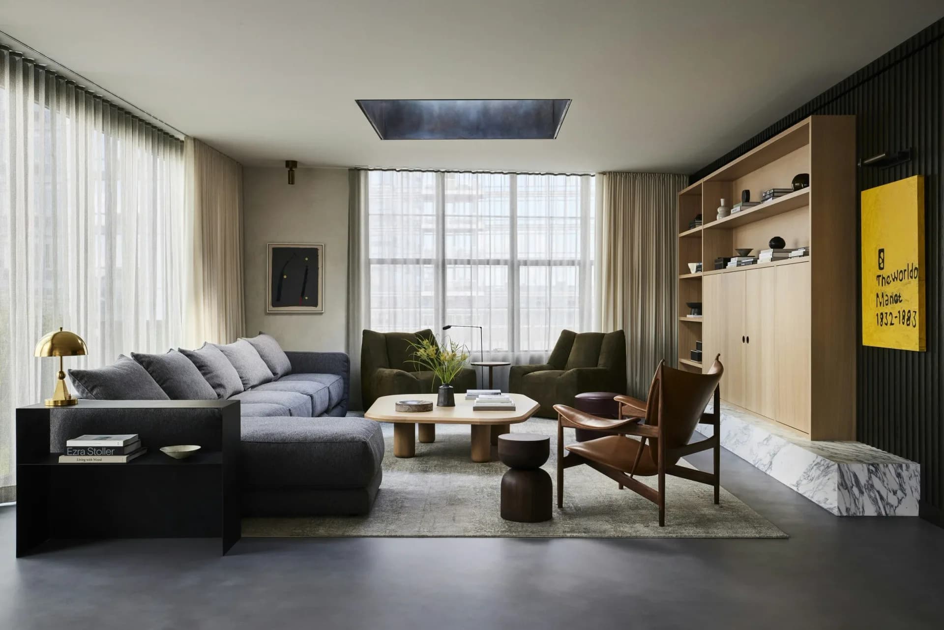 Modern living room with dark sectional sofa, wooden shelving, black accent wall, large windows, and contemporary furnishings in a neutral palette by Gretchen Kubiak.