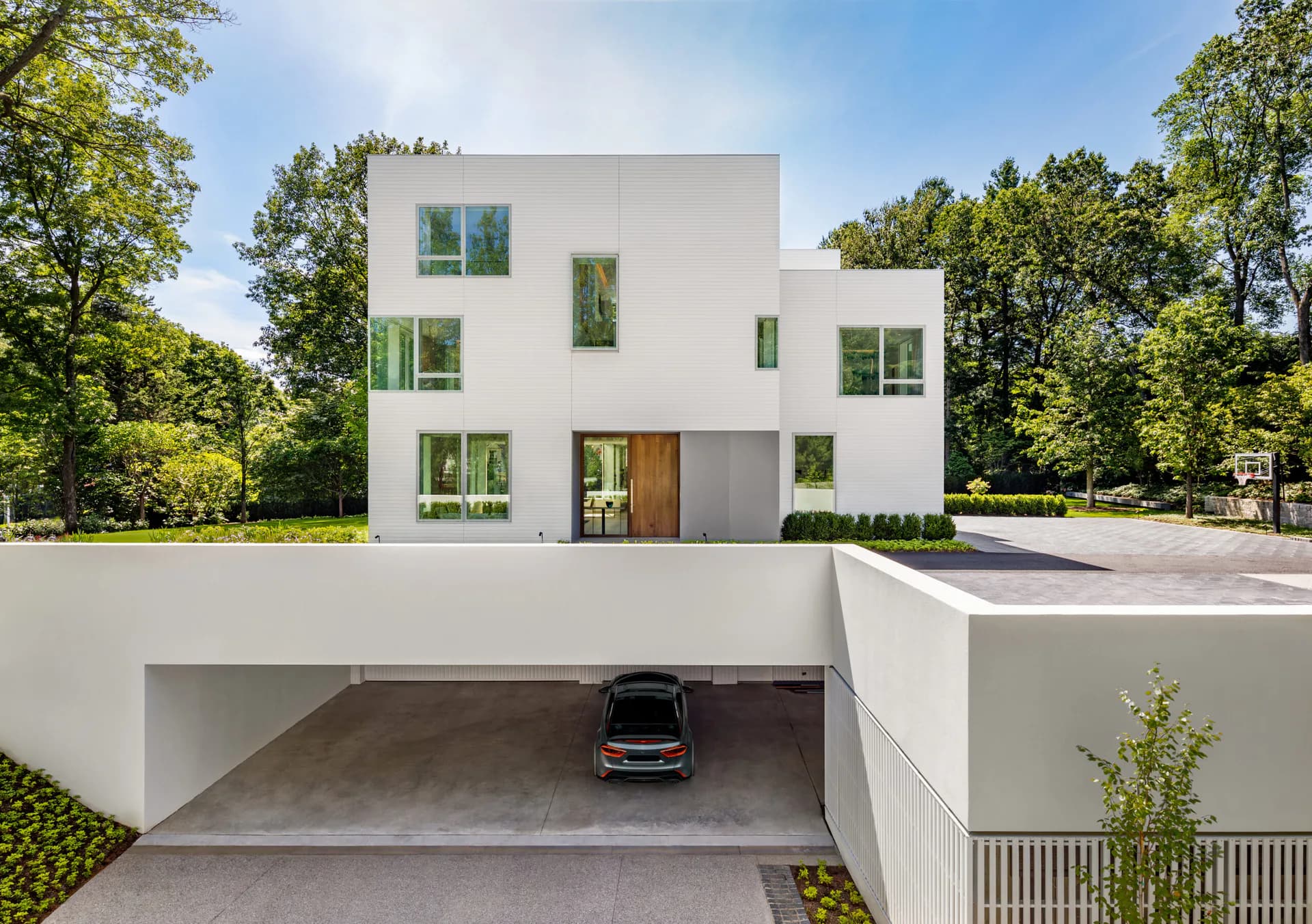 Modern white cubic residential building with integrated garage and green window frames surrounded by trees, by Gwendolyn Conners.