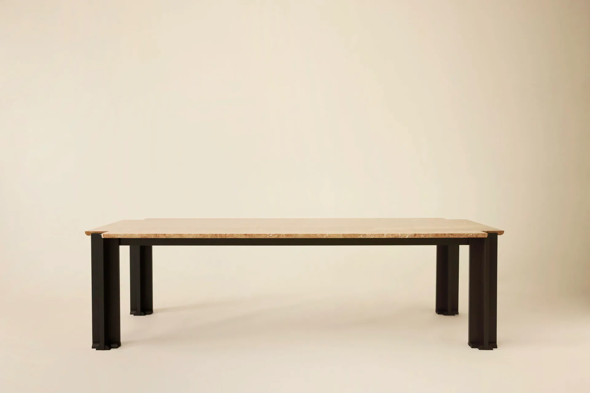Minimalist dining table with light wood top and dark cylindrical legs against neutral background by Hillary Petrie.
