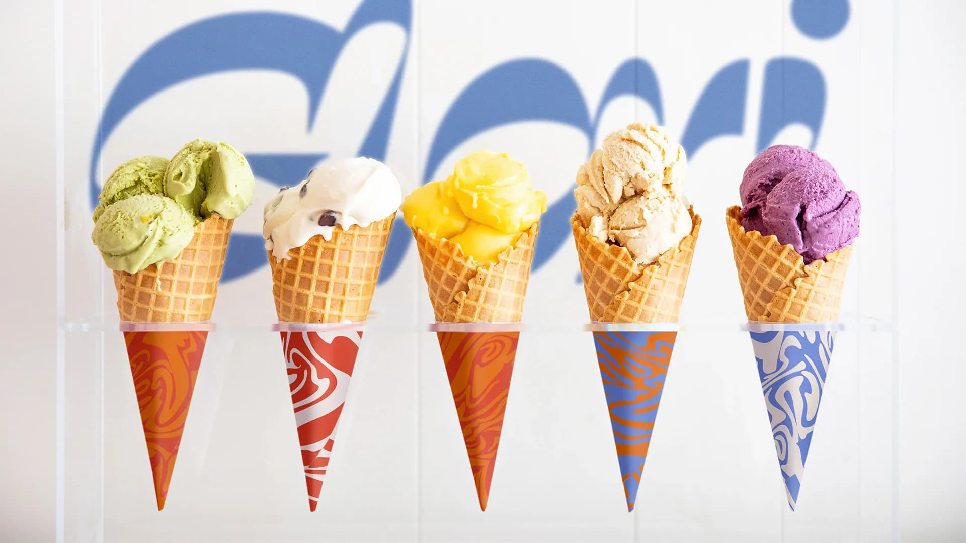 Five colorful ice cream cones with different flavors displayed against a blue branded background, showcasing product design and branding work by Hines Fischer.
