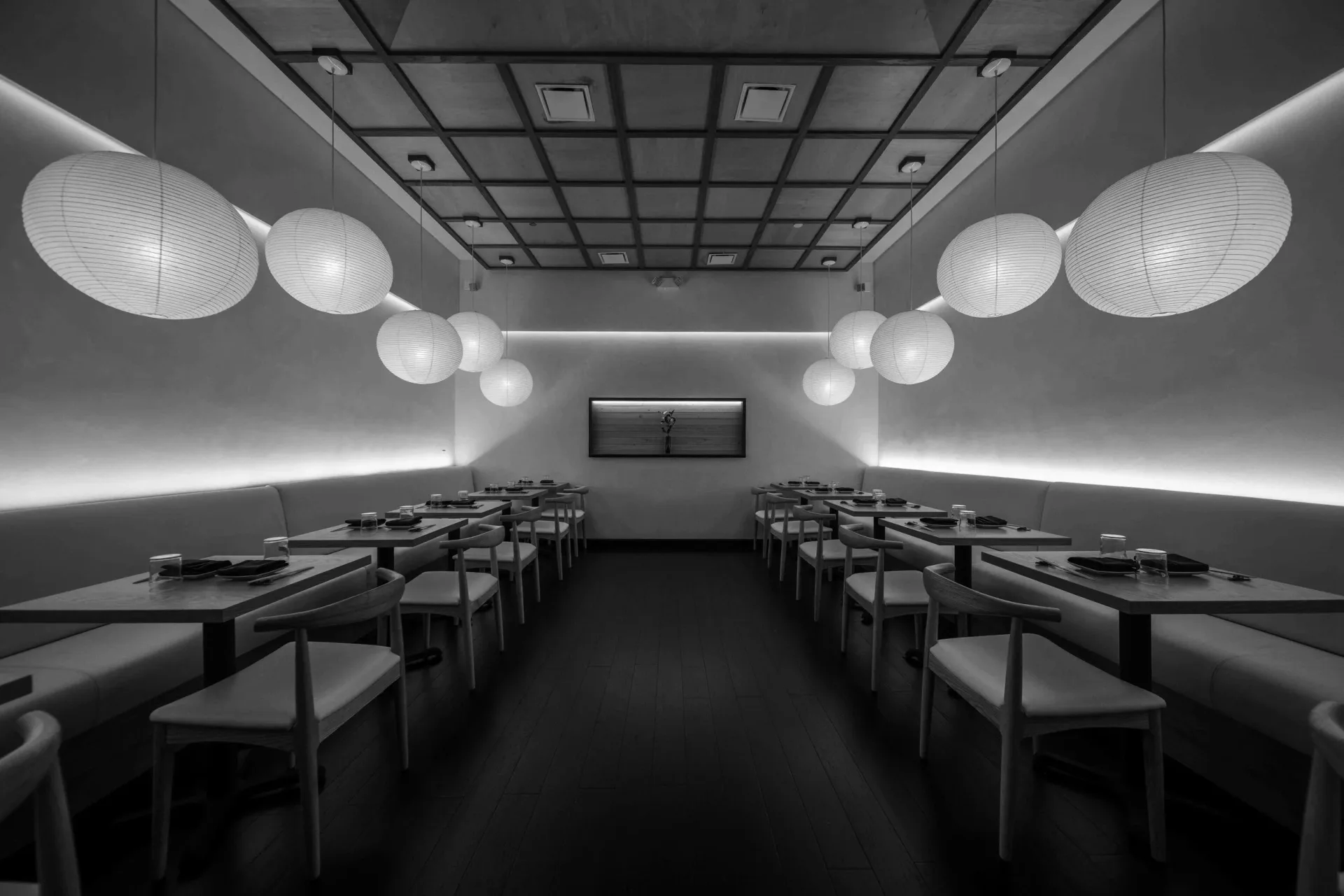 Symmetrical monochromatic cinema interior with rows of seating, spherical pendant lights, and linear ceiling elements by Ian Bentley.