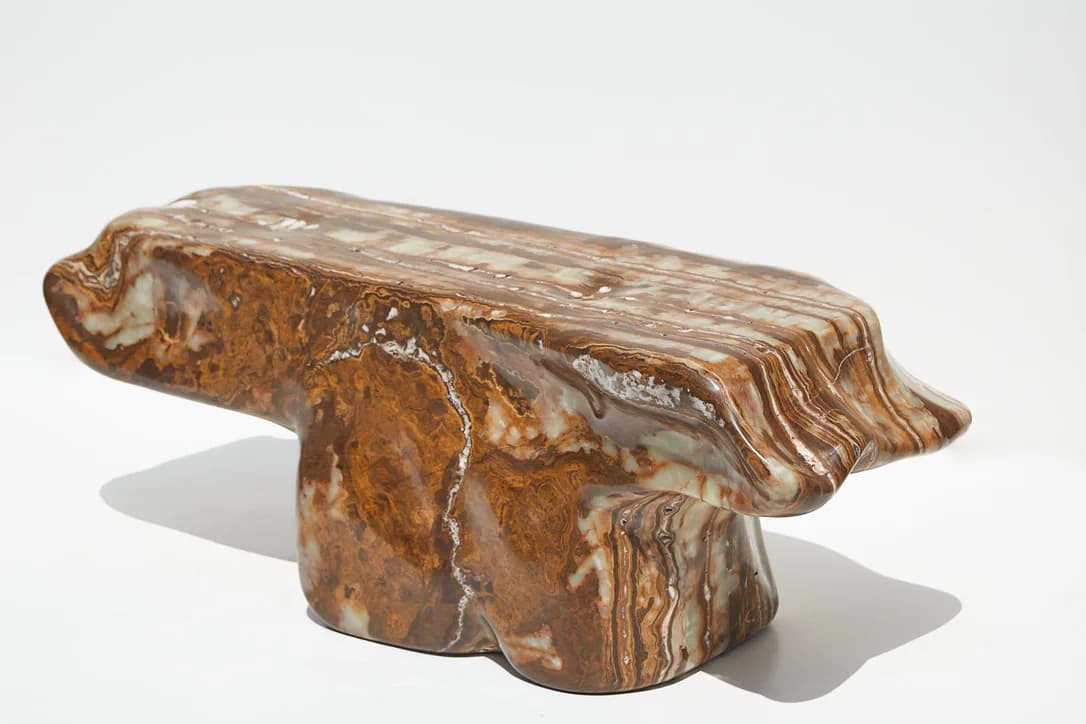 Sculptural wooden bench with organic, flowing forms and striped grain patterns in warm brown tones by Ian Collings.